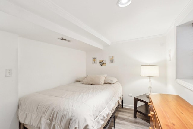 bedroom with crown molding, light wood-style floors, and visible vents