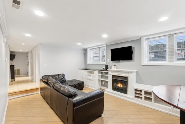 living area with a glass covered fireplace, recessed lighting, visible vents, and wood finish floors