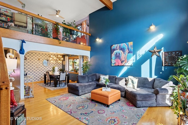 living area with a high ceiling, wood finished floors, beamed ceiling, and ceiling fan