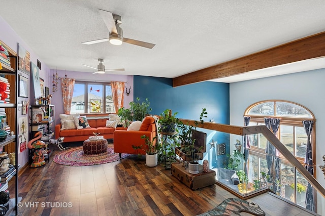 living area featuring beamed ceiling, wood-type flooring, and a textured ceiling