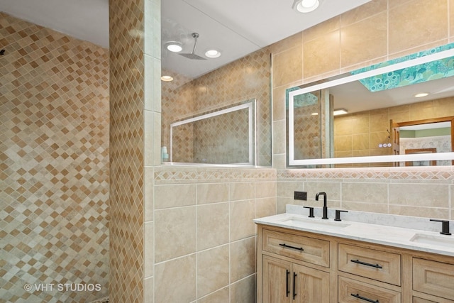 bathroom featuring a sink, tile walls, double vanity, and a shower stall