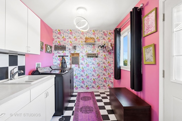 clothes washing area featuring wallpapered walls, cabinet space, a sink, washer and dryer, and tile patterned floors