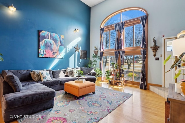 living room with wood finished floors and a towering ceiling