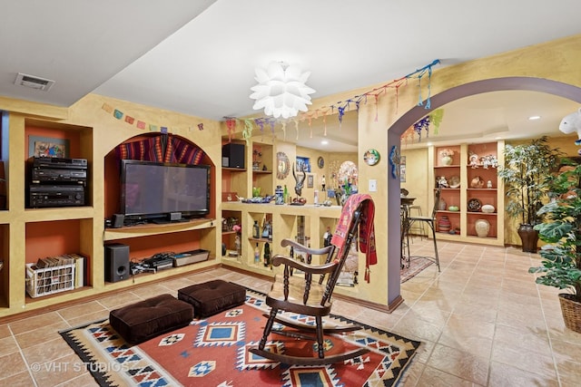 living room featuring arched walkways, built in features, and visible vents