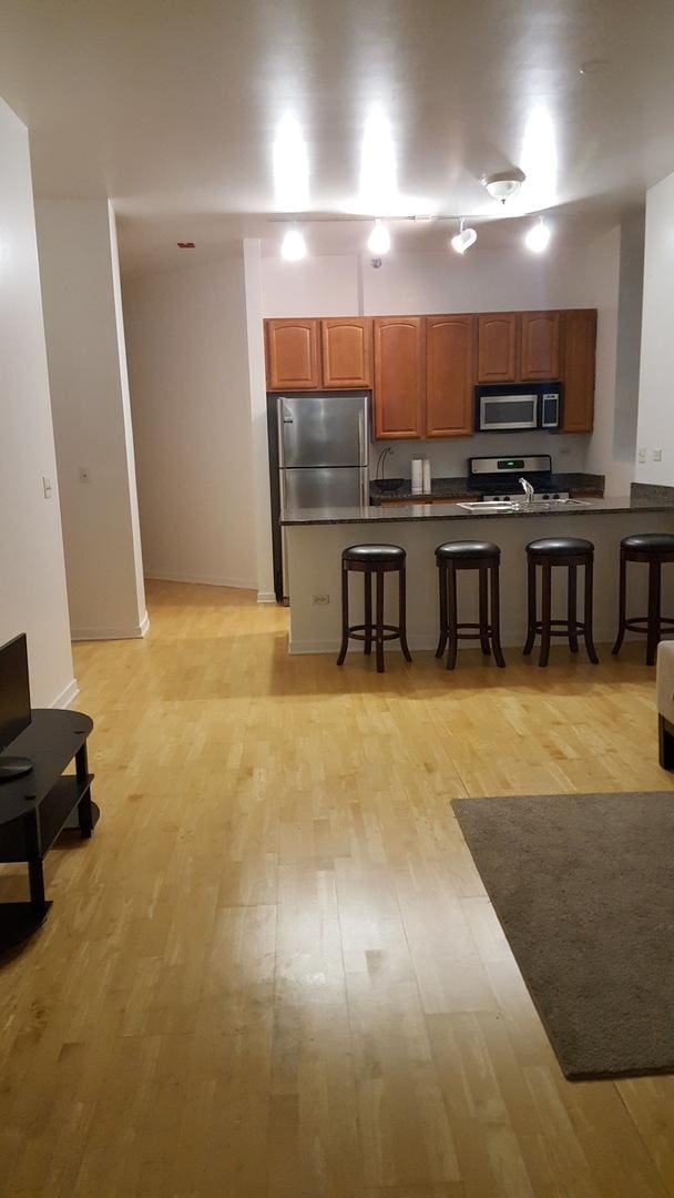 kitchen featuring light wood-type flooring, stainless steel appliances, and a kitchen breakfast bar