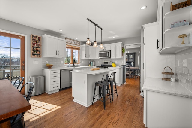 kitchen featuring open shelves, wood finished floors, a center island, white cabinetry, and stainless steel appliances