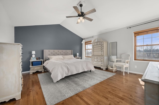 bedroom featuring vaulted ceiling, multiple windows, baseboards, and wood finished floors