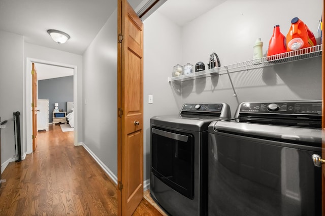 laundry area with laundry area, wood finished floors, baseboards, and washer and clothes dryer