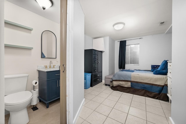 bedroom with visible vents, baseboards, light tile patterned floors, wet bar, and a sink