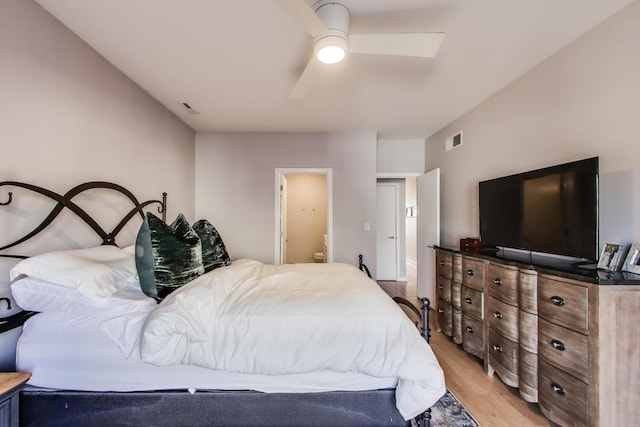 bedroom with light wood finished floors, visible vents, ensuite bathroom, and ceiling fan