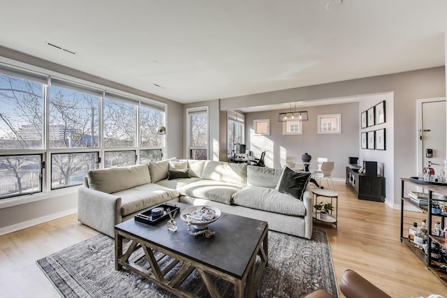 living area with a wealth of natural light, baseboards, and light wood-style floors