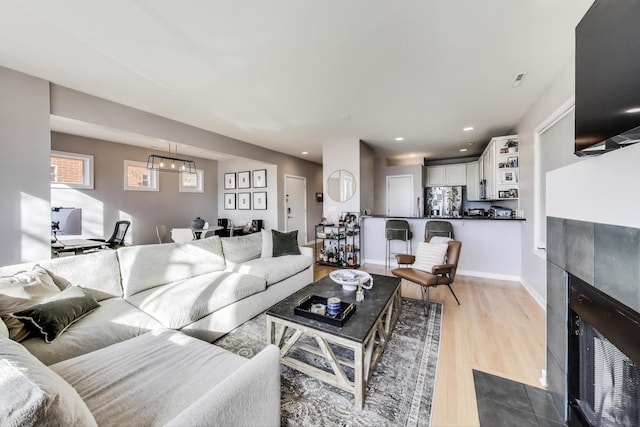 living room featuring recessed lighting, wood finished floors, baseboards, and a tile fireplace