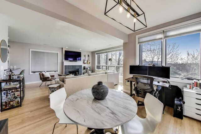 dining area featuring light wood-style flooring, a tile fireplace, and baseboards