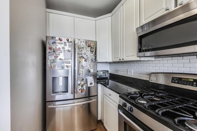 kitchen featuring tasteful backsplash, white cabinetry, stainless steel appliances, and dark stone counters