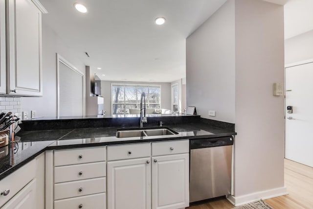 kitchen with stainless steel dishwasher, light wood finished floors, white cabinetry, and a sink