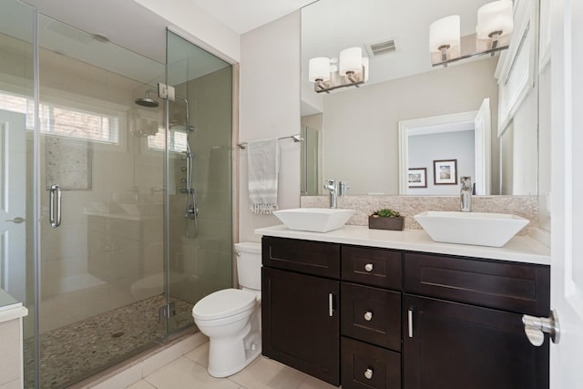 bathroom featuring a sink, toilet, a stall shower, and double vanity