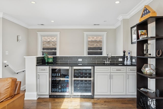 bar featuring beverage cooler, wet bar, crown molding, and a sink