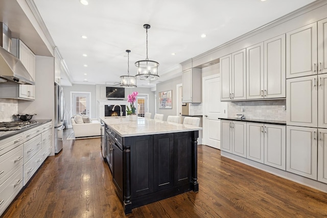 kitchen featuring dark wood finished floors, open floor plan, a warm lit fireplace, appliances with stainless steel finishes, and dark cabinets