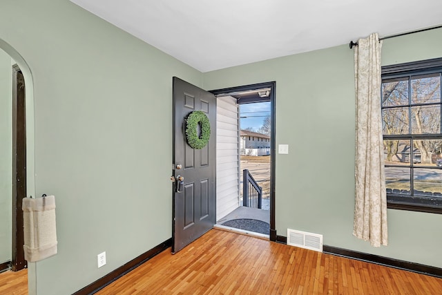 foyer entrance featuring visible vents, arched walkways, plenty of natural light, and light wood-style flooring