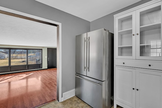 kitchen featuring light wood-type flooring, baseboards, visible vents, and high end refrigerator