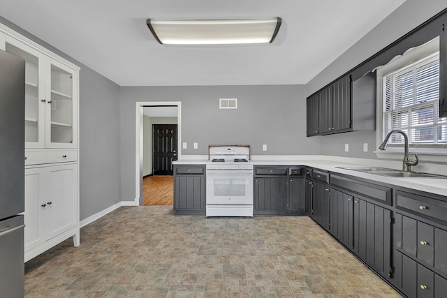 kitchen featuring visible vents, white gas stove, gray cabinetry, a sink, and light countertops