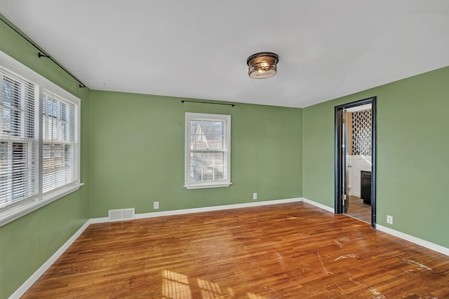 empty room featuring visible vents, baseboards, and wood finished floors