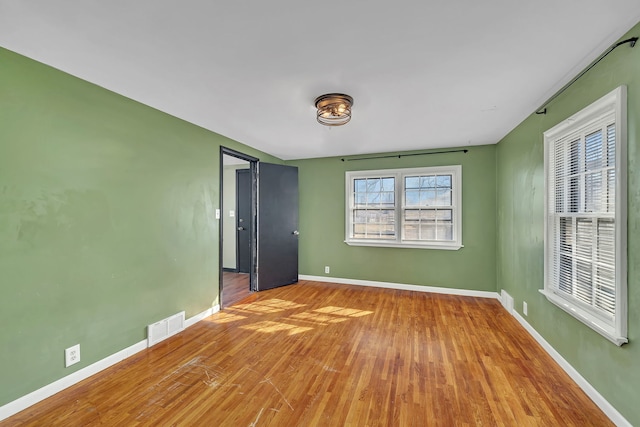 unfurnished room featuring visible vents, baseboards, and wood finished floors