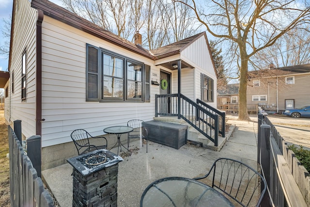 back of property with fence, a chimney, and an outdoor fire pit