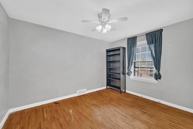 unfurnished room featuring visible vents, baseboards, wood finished floors, and a ceiling fan