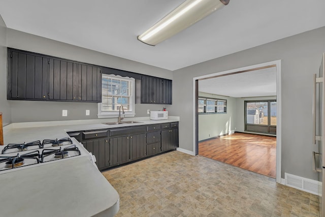 kitchen with a sink, visible vents, white microwave, and light countertops