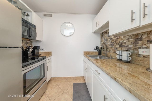 kitchen with decorative backsplash, stainless steel range with electric stovetop, a sink, black microwave, and freestanding refrigerator