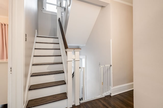 staircase featuring crown molding, wood finished floors, and baseboards