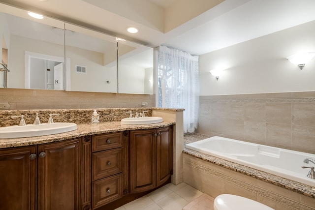 bathroom with double vanity, a relaxing tiled tub, visible vents, and a sink