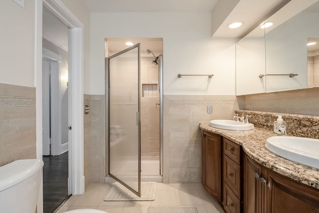 full bath featuring tile walls, a shower stall, and a sink