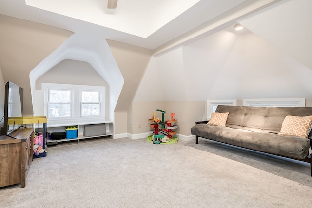 carpeted living area with baseboards, lofted ceiling, and a ceiling fan