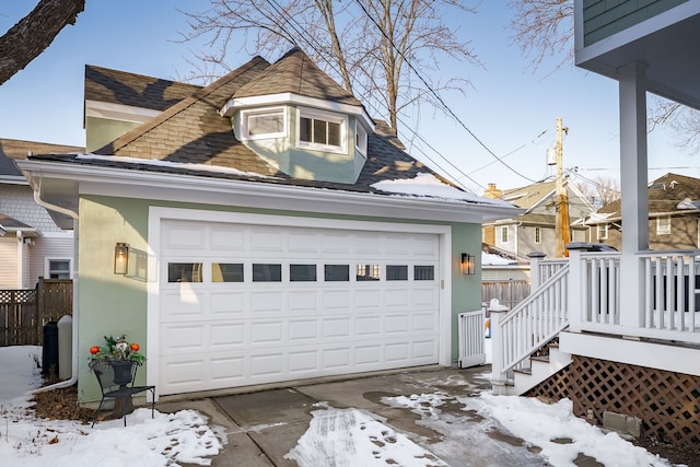 snow covered garage featuring fence and driveway