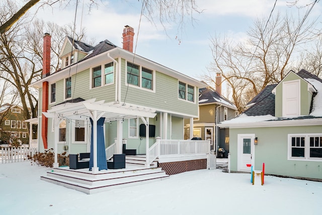 view of front facade featuring fence, covered porch, a chimney, an outdoor structure, and a storage unit