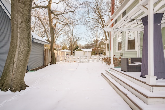 snowy yard with a residential view, an outbuilding, and fence