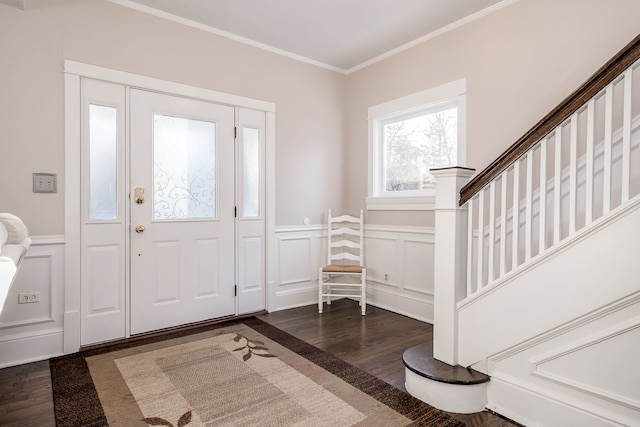 foyer featuring dark wood finished floors, a wainscoted wall, a decorative wall, and ornamental molding