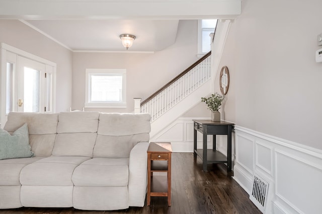 living area with crown molding, dark wood finished floors, stairway, wainscoting, and a decorative wall