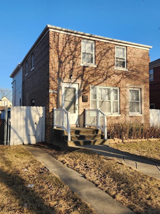 view of front of house featuring fence and brick siding