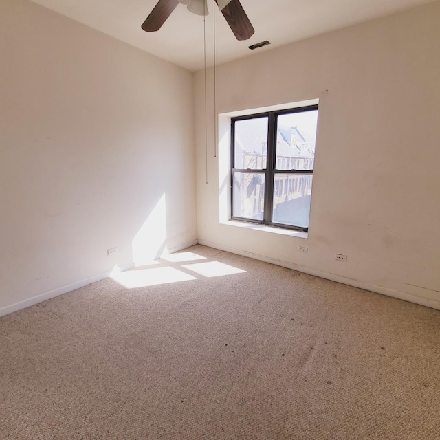 carpeted spare room featuring visible vents, baseboards, and ceiling fan