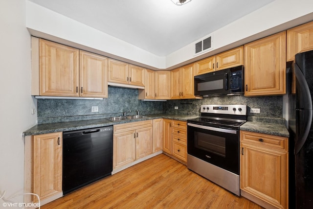 201 E Chestnut St Unit 14E, Chicago, IL 60611 - kitchen with black appliances, a sink, dark countertops, and light wood-style floors