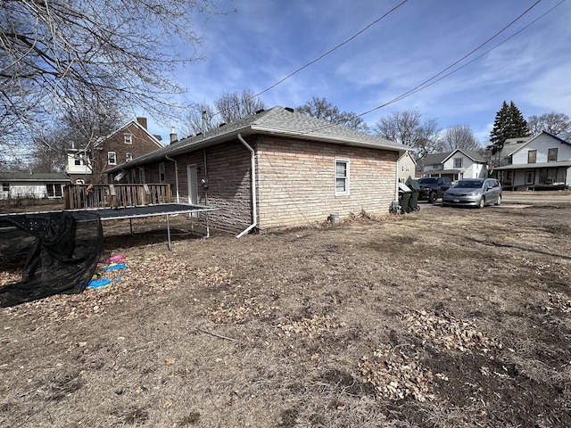 view of side of property featuring stone siding and a shingled roof