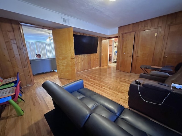 living area featuring wooden walls, wood finished floors, and visible vents