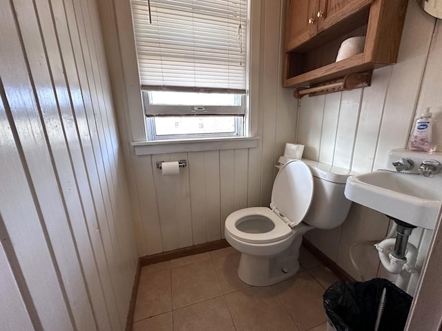 half bath with tile patterned flooring, toilet, and baseboards