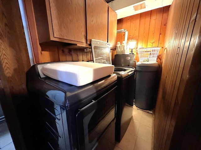 laundry room featuring light tile patterned flooring, cabinet space, independent washer and dryer, and wood walls