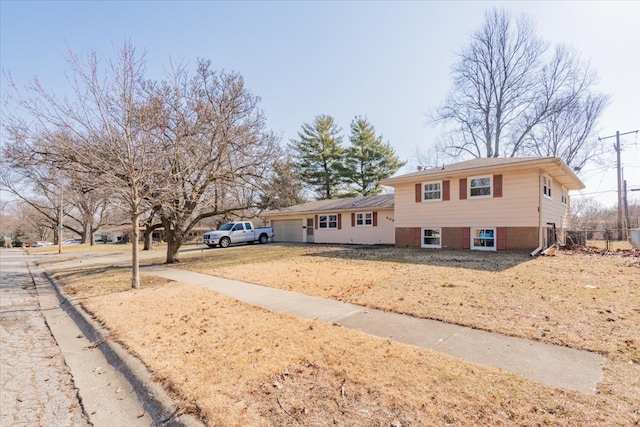 tri-level home with concrete driveway, an attached garage, fence, and brick siding