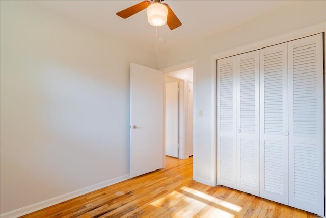 unfurnished bedroom with ceiling fan, a closet, baseboards, and light wood-style flooring