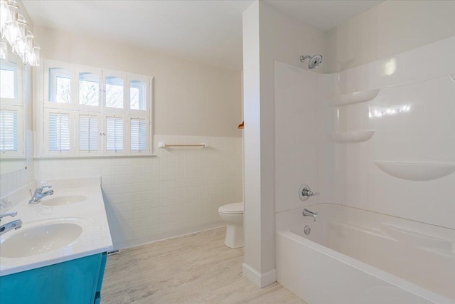 full bathroom with toilet, a healthy amount of sunlight, and a sink